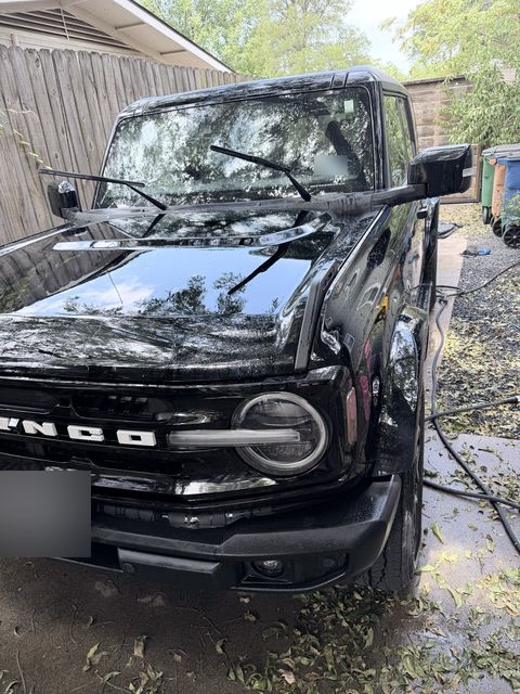 A black Ford Bronco being rinsed in a North Austin driveway