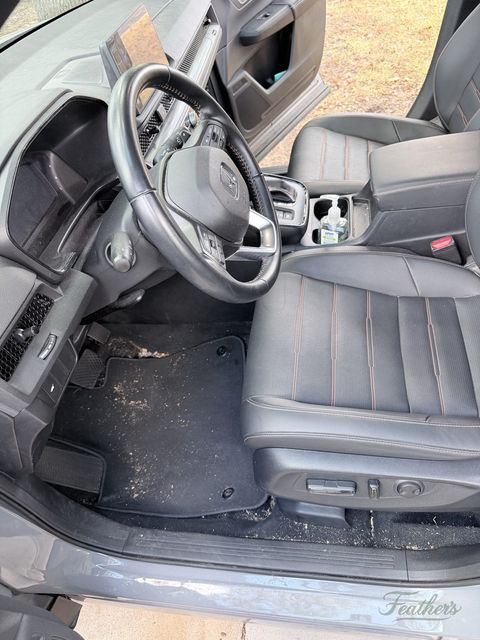 Driver footwell of a Honda CR-V before cleaning, grit and debris worked into the carpet