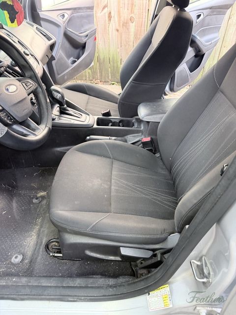 Driver seat and footwell of a Ford Focus with the door open, grit through the carpet